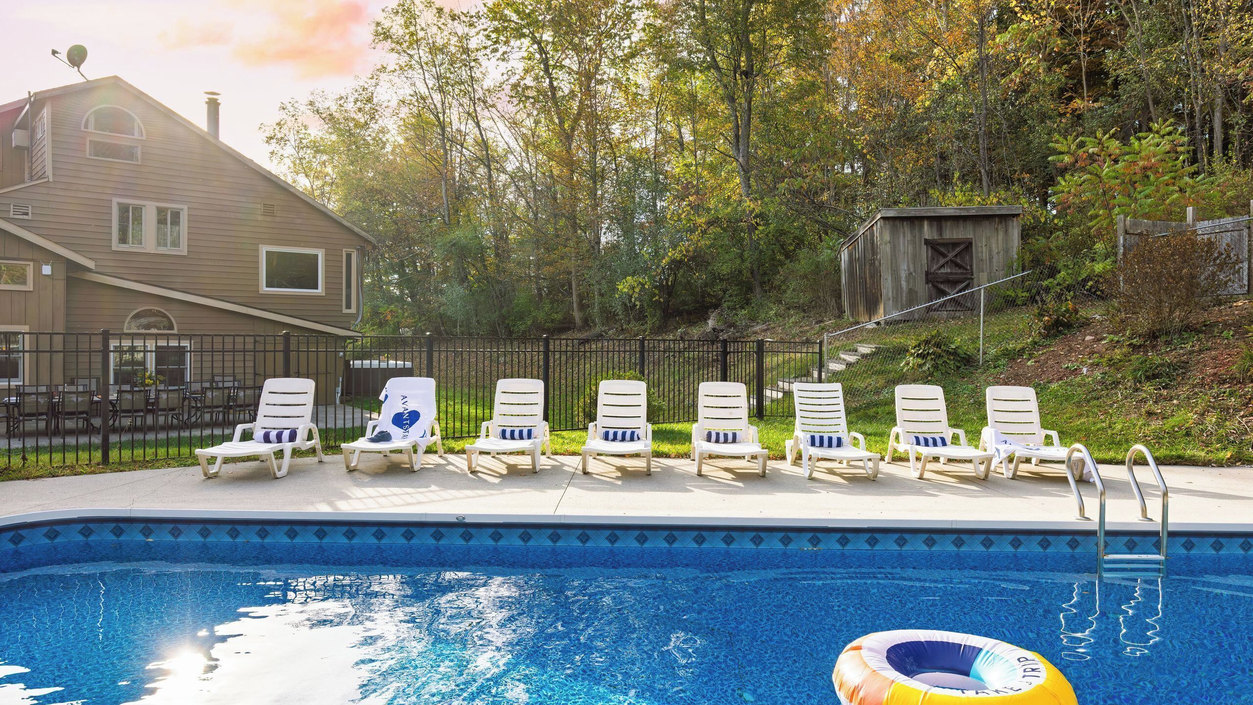 A swimming pool with lounge chairs and a house in the background.