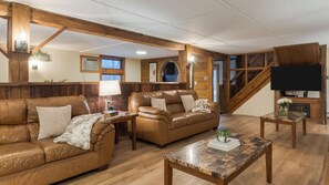 A cozy living room with leather sofas, a coffee table, and wooden beams. - Sleeps 40 Heated Pool Hot Tub Fire Pit Game Room Brookside Mountain Retreat by Avantstay (Stephentown)