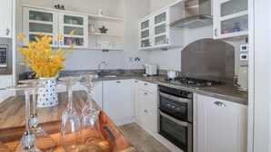 A modern kitchen with white cabinetry, a wooden countertop, and a gas stove. - 1 Fishermans Hill (Newton Stewart)