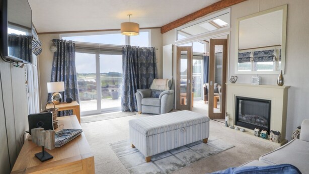 A spacious living room with a large window, a fireplace, and a cozy seating area. - 1 Fishermans Hill (Newton Stewart)
