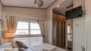 A hotel room with a bed, curtains, a television, and a wardrobe. - 1 Fishermans Hill (Newton Stewart)