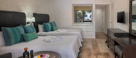 A hotel room with two beds, a TV, a desk, and a window with a view.