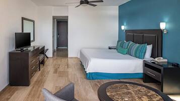 Une chambre d’hôtel équipée d’un lit, d’une table de chevet, d’un bureau, d’une télévision et d’un ventilateur de plafond.