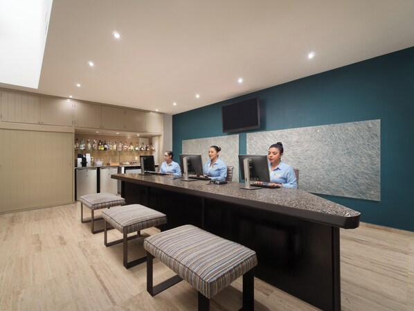 A bar area with three bar stools, a counter, and a television mounted on the wall. - El Cid Castilla Beach Hotel - All Inclusive (Mazatlán)