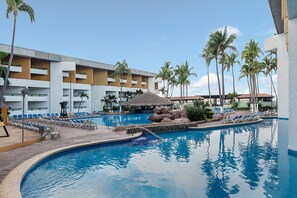 A resort pool area with lounge chairs, palm trees, and a building with balconies. - El Cid Castilla Beach Hotel - All Inclusive (Mazatlán)