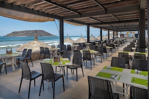 An outdoor dining area with tables and chairs, overlooking the ocean. - El Cid Castilla Beach Hotel - All Inclusive (Mazatlán)