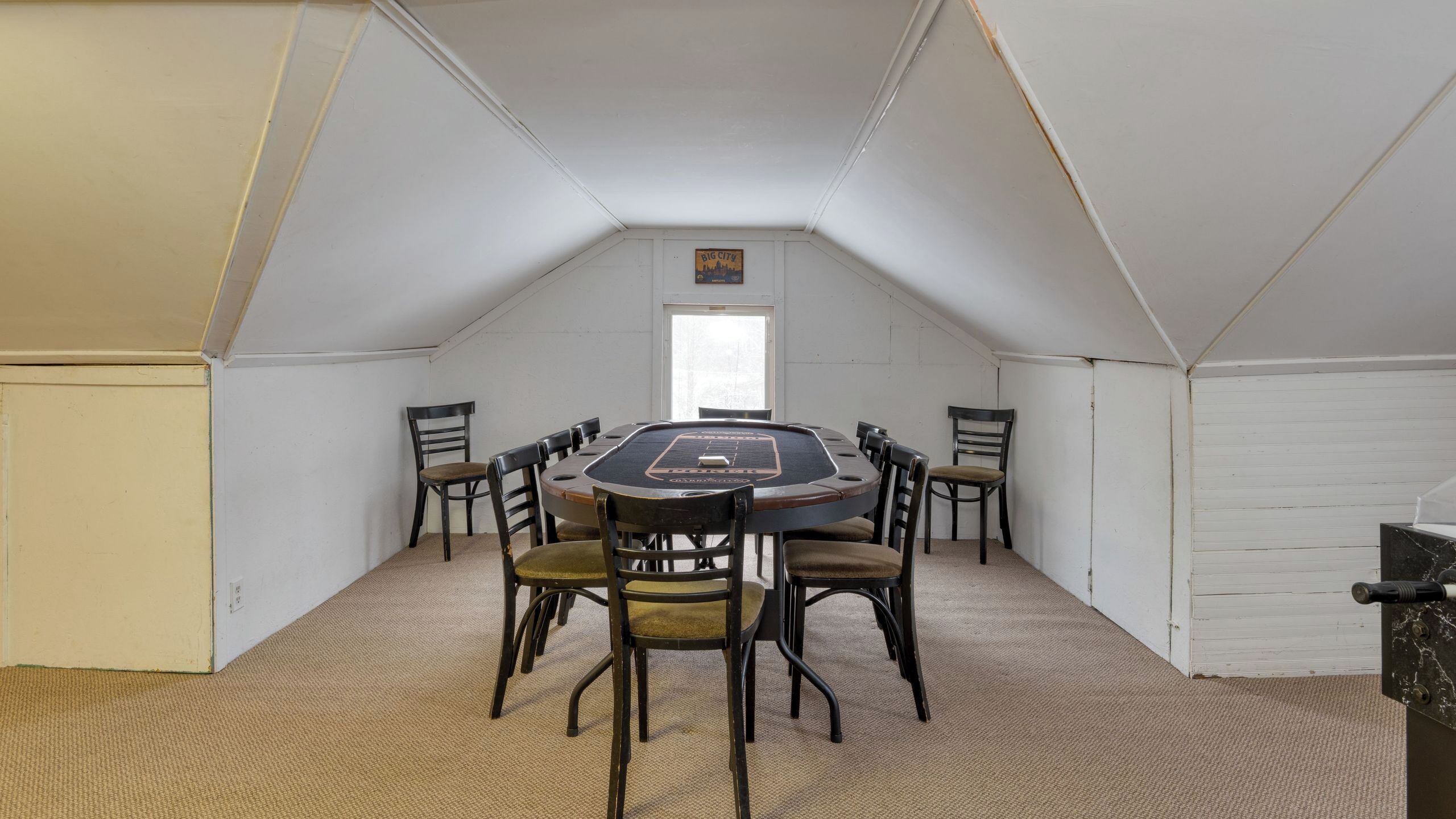 A conference room with a large oval table, eight chairs, and a white ceiling.