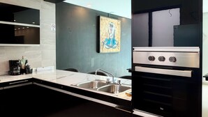 Una cocina moderna con armarios negros, un lavamanos de acero inoxidable y un horno empotrado.