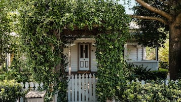 A house partially covered by a white picket fence and dense green foliage.