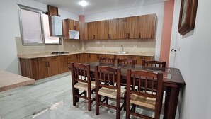 A modern kitchen with wooden cabinets, a dining table with chairs, a built-in oven, and a window. - Depas Ocampo de Grupo Casa Mariano (Morelia)