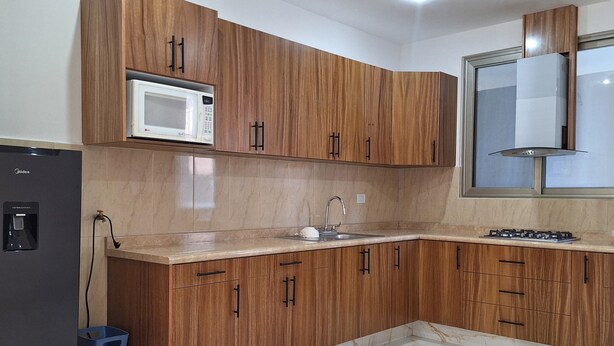 A modern kitchen with wooden cabinets, a built-in microwave, a sink, and a gas stove. - Depas Ocampo de Grupo Casa Mariano (Morelia)