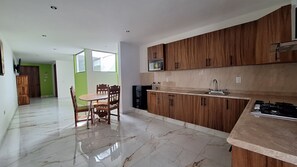A modern kitchen with wooden cabinets, a marble countertop, and a dining area with a table and chairs. - Depas Ocampo de Grupo Casa Mariano (Morelia)