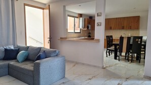 A living room with a grey sofa, a dining area with a table and chairs, and a kitchen with wooden cabinets. - Depas Ocampo de Grupo Casa Mariano (Morelia)