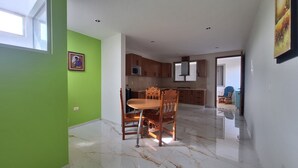 A spacious kitchen with wooden cabinets, a dining area with a marble floor, and a green wall. - Depas Ocampo de Grupo Casa Mariano (Morelia)