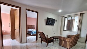 A spacious living area with a sofa, a wooden table, and a TV mounted on the wall. - Depas Ocampo de Grupo Casa Mariano (Morelia)
