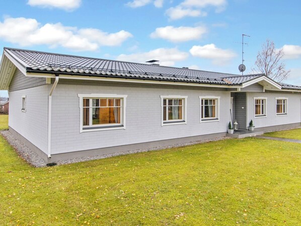 A single-story house with a grey tiled roof, white siding, and a small front porch. - Villa kupsala by Interhome (Juva)
