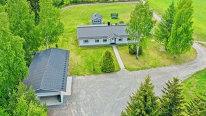 Une grande maison avec un vaste jardin devant, un garage séparé et une vue sur un lac.