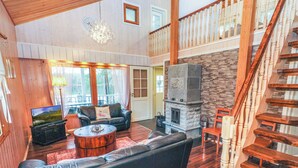 Ein geräumiges Wohnzimmer mit Kamin aus Stein, Ledersofas und einer Holztreppe.