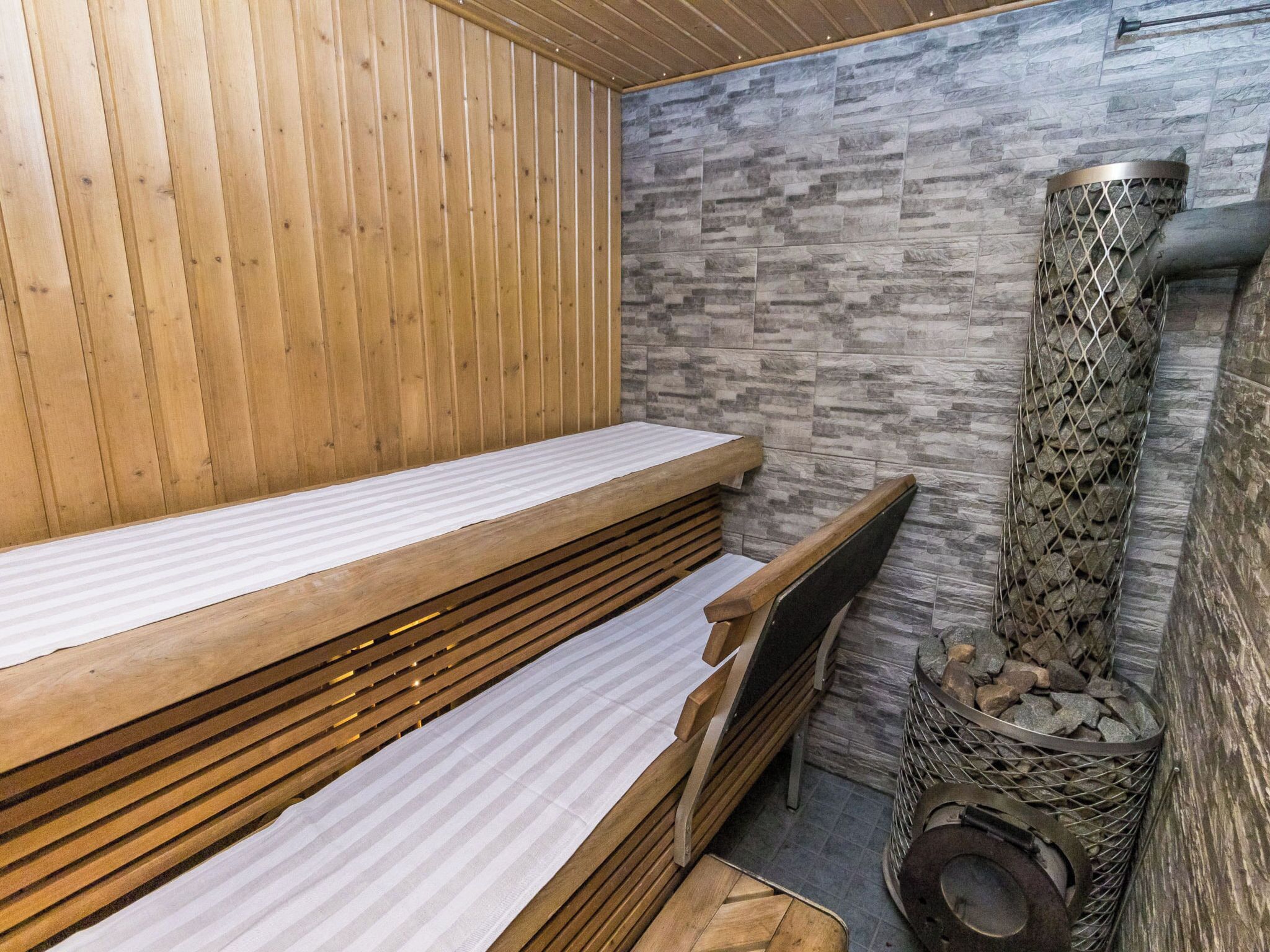 Una sauna con bancos de madera y una pared de piedra.