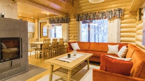 L’intérieur d’une cabane en rondins, avec une cheminée, des meubles en bois et un coin salon confortable.