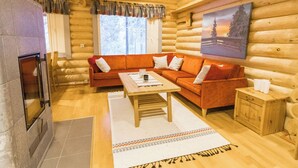 L'intérieur d'une cabane en rondins, avec un canapé en bois, une table basse, une cheminée et un tableau accroché au mur.