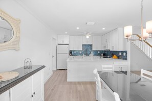 A modern kitchen with white cabinetry, a central island, and a blue backsplash. - Spacious Two-Story Townhome with Private Beach Access at Seashells of Sanibel (Sanibel)