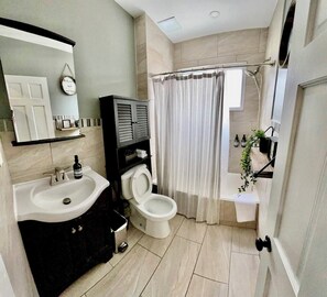 A modern bathroom with a sink, toilet, and shower area. - 4BR Home with Free Parking + Outdoor Fenced Patio (Philadelphia)