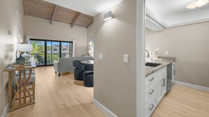 A spacious living area with a dining table, a kitchen with white cabinets, and a large sliding glass door leading to an outdoor area. - Coquina Beach- Stunning Remodel-2 Bedroom- Beachside (Sanibel)