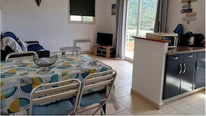 Una camera da letto con un letto, una TV, un tavolino e un angolo cottura.