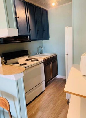 A compact kitchen with a stove, sink, and dark cabinets. - Cozy 1bd/1ba- great for long term guests (Waco)