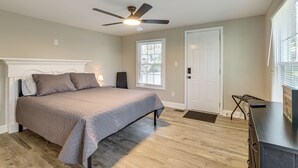 Une chambre à coucher comprenant un lit, un ventilateur de plafond, une fenêtre, une porte et une commode.