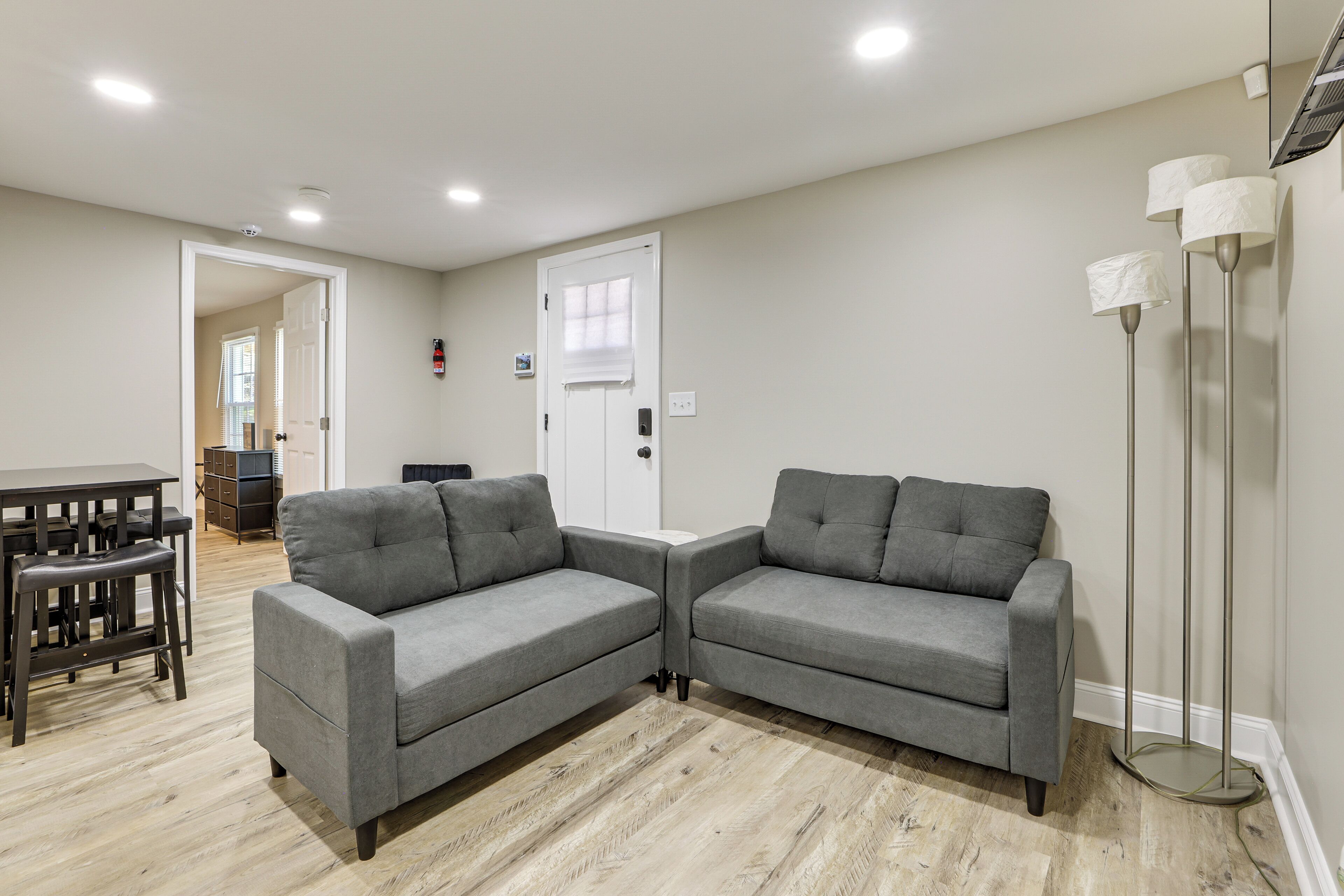 A modern living room with a gray sectional sofa, a dining table with chairs, and a tall floor lamp.