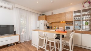 Une cuisine compacte avec un coin repas, des meubles blancs, un four à micro-ondes et un téléviseur.