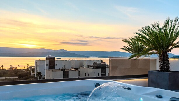 Un bain à remous avec vue sur un plan d’eau et des montagnes, au coucher du soleil.