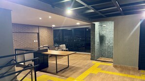 Un interior moderno con pared de ladrillo, separador de vidrio y vista nocturna de la ciudad.