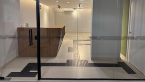 Un espacio de oficina moderno con mostrador de recepción, separaciones de vidrio y suelo de baldosas limpias.