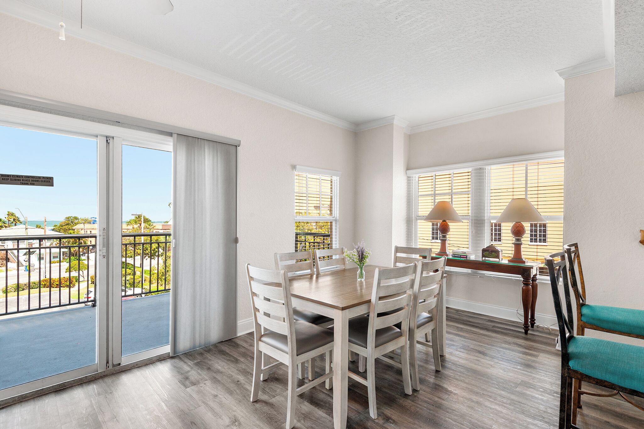 A dining area with a table and chairs, a view of the outdoors, and a balcony with a railing.