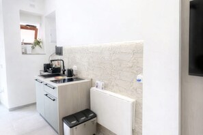 Eine kompakte Küche mit Einbauherd, Spüle und Mülleimer.