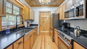 Eine moderne Küche mit Holzausstattung, einem Edelstahlkühlschrank und einem Gasherd.