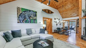 Ein geräumiges Wohnzimmer mit einem großen Ecksofa, einem runden Couchtisch und einer Holzbalkendecke.