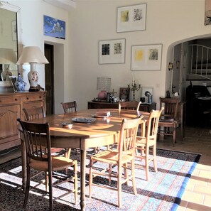 A dining area with a wooden table and chairs, a patterned rug, and a kitchen area with a stove and cabinets. - Villa-Superior-Ensuite-Park view- 3 chambres (La Garde-Freinet)