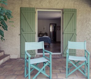 A room with a bed, a small table, and a chair. There are two green doors leading to the room. - Villa-Superior-Ensuite-Park view- 3 chambres (La Garde-Freinet)