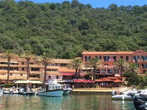 A coastal hotel with multiple buildings, a marina with boats, and a backdrop of dense green hills. - Villa-Superior-Ensuite-Park view- 3 chambres (La Garde-Freinet)