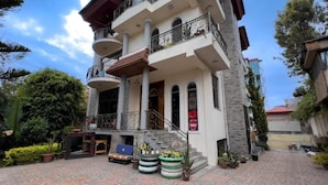 Un immeuble à plusieurs étages doté d’un balcon, d’un escalier et d’un petit espace extérieur aménagé en coin salon.
