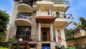 Un immeuble à plusieurs étages doté de balcons, avec un commerce au rez-de-chaussée et un hall d’entrée carrelé.