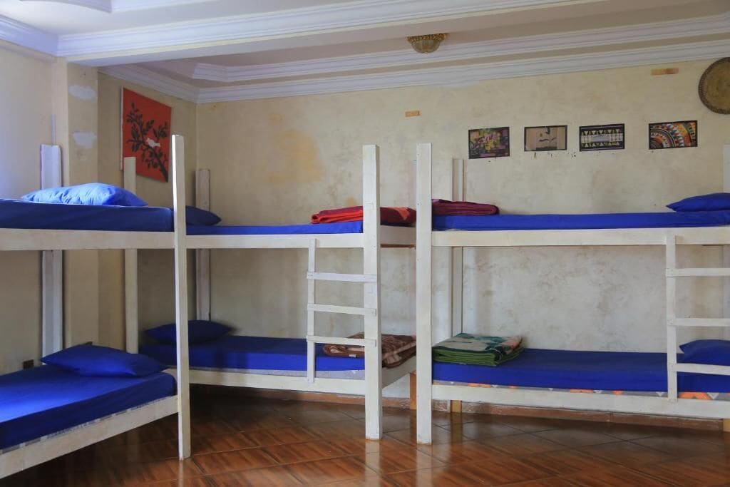A dormitory room with bunk beds, wooden railings, and a tiled floor.