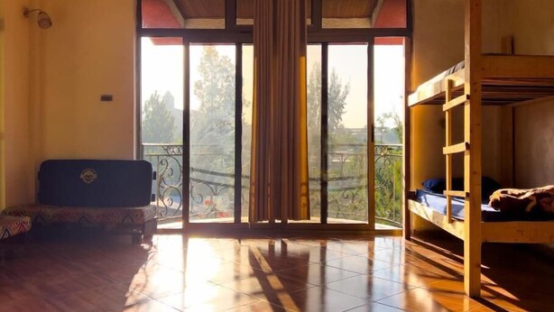 Une chambre dotée d’une grande porte-fenêtre coulissante donnant sur un balcon, d’un lit superposé et d’un canapé.
