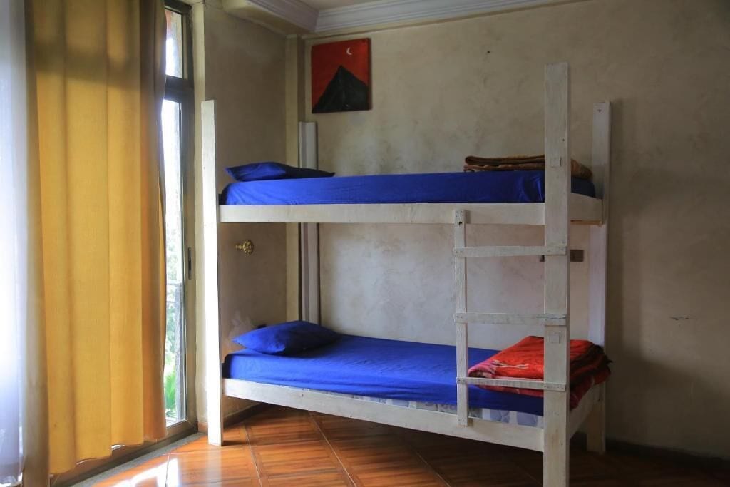 Ein Schlafraum mit Etagenbetten, Fenster und Tür.