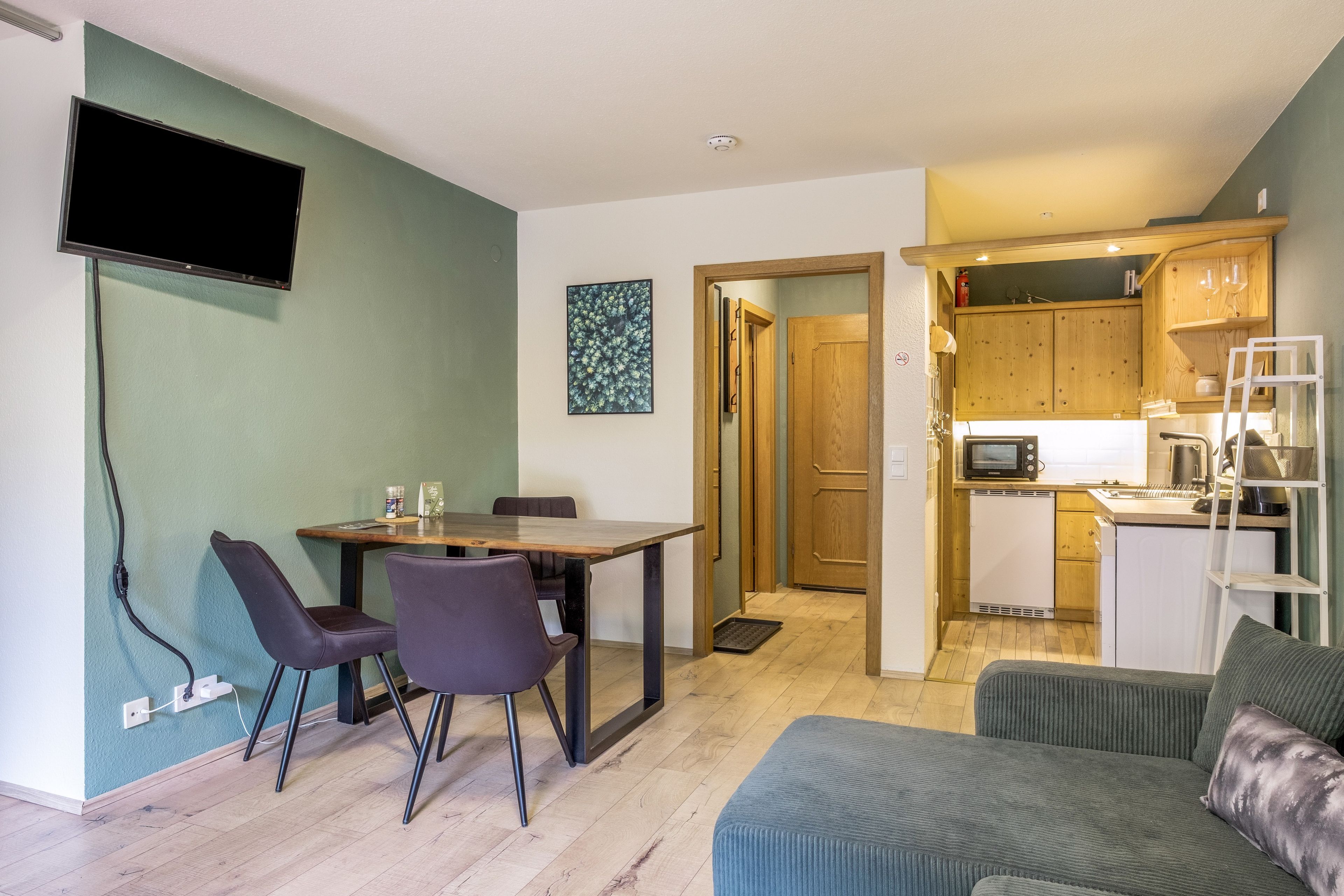 Een knus woongedeelte met een eethoek, kitchenette en een bank.