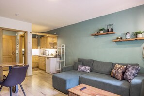 A compact living space with a kitchenette, a dining area, and a seating area with a sofa and a coffee table.